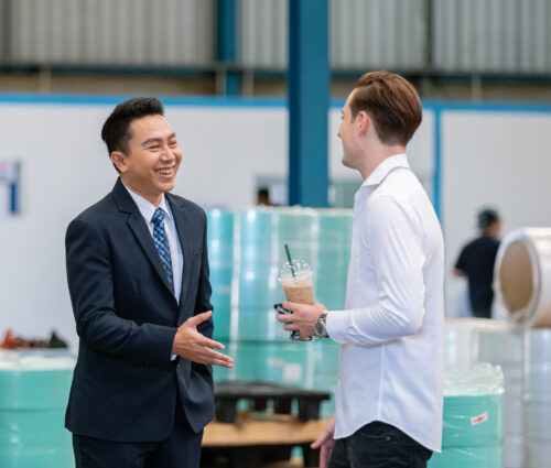 Businessman and partner talking at mask factory industry manufacturing line produces. manager and inspector meeting concept.